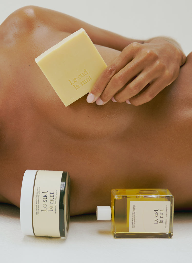 Rituel de soins pour le corps Le sud la nuit de chez Refeel Naturals composé de l'huile sèche, du savon crémeux et du gommage lacté, tenus par le mannequin